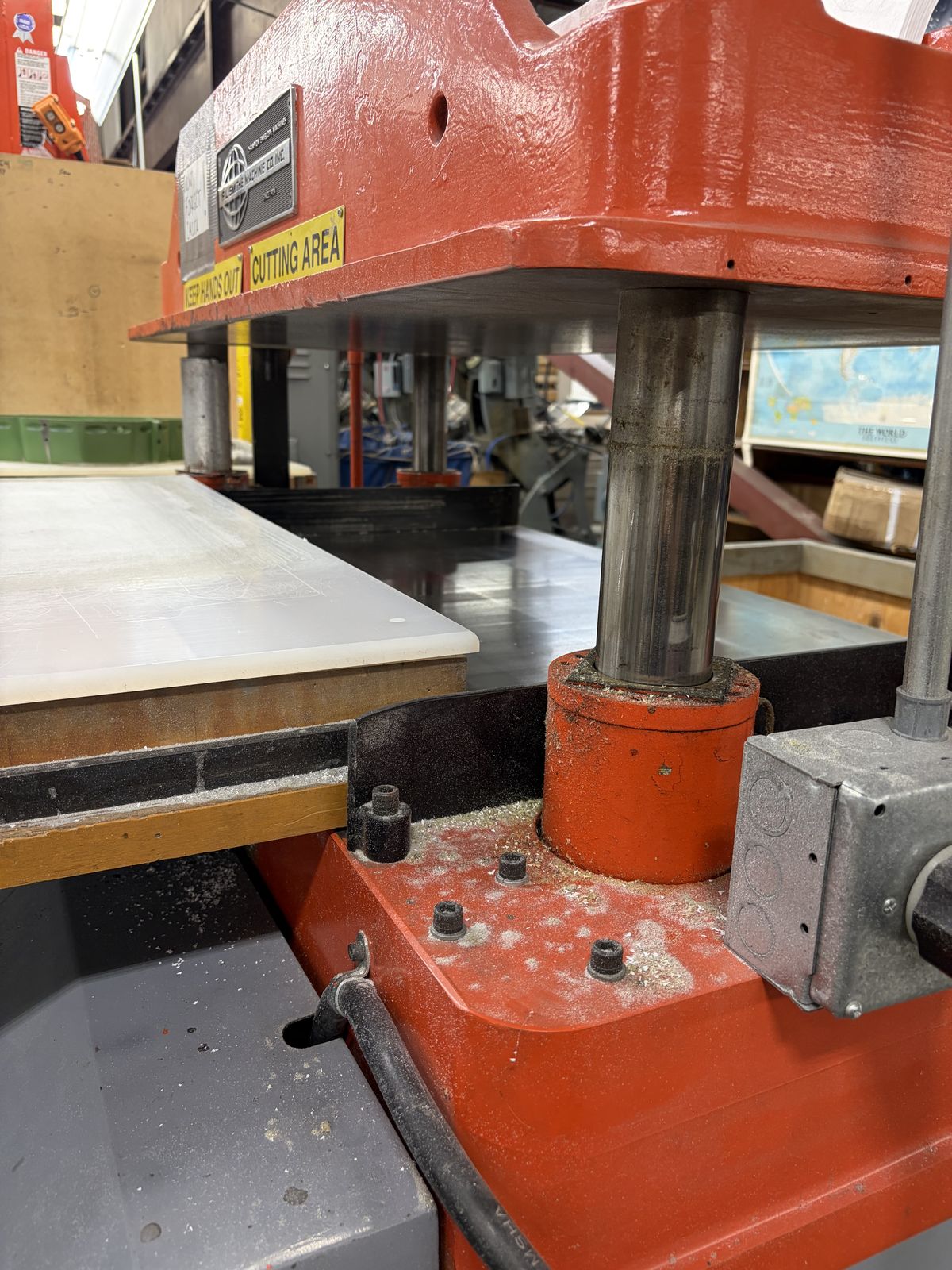 The cutting area of a heavy orange stock cutter machine.