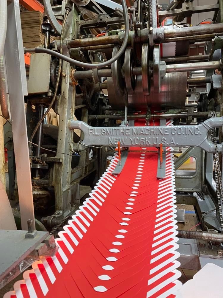 An F.L. Smithe envelope machine at Envelope Converting Service, running red printed blanks through the folding and gluing section.