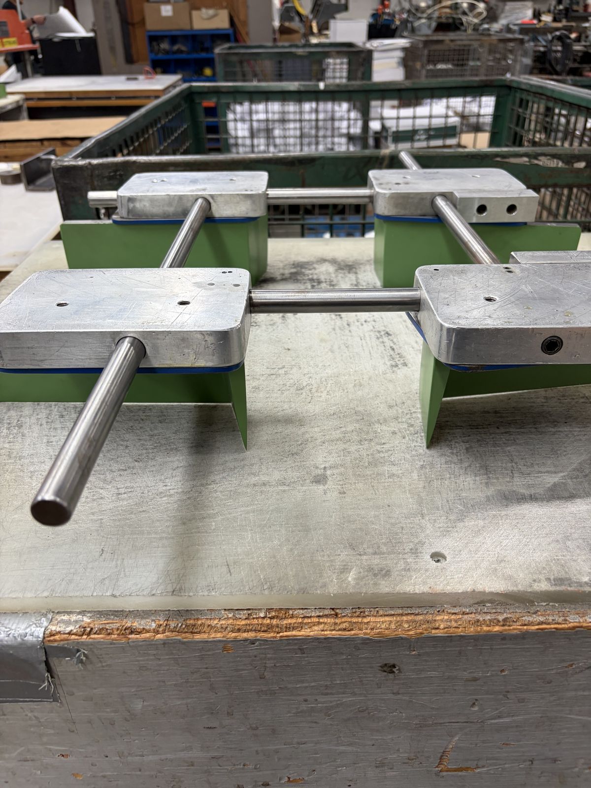 An adjustable spider die with aluminum blocks on a green base, sitting on a workbench.